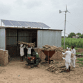"Biofuel facility in a rural Indian landscape with farmers and agricultural feedstock."