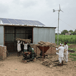 "Biofuel facility in a rural Indian landscape with farmers and agricultural feedstock."