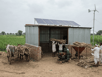 "Biofuel facility in a rural Indian landscape with farmers and agricultural feedstock."