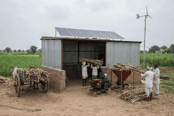 "Biofuel facility in a rural Indian landscape with farmers and agricultural feedstock."