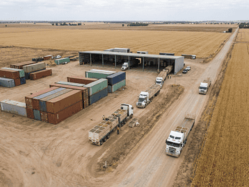 Neutral aerial view of Australian agricultural export logistics showing containers and produce transport